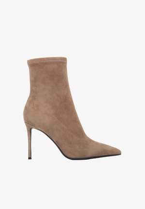 Beżowy zamszowy botek na kostkę z zaostrzonym noskiem i obcasem szpilką. Elegancki, dopasowany design z bezszwową cholewką i minimalnymi detalami szwów.
