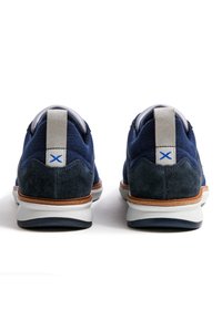 Baskets bleu marine avec un mélange de tissu texturé et de suède, semelle blanche, et languette grise avec un accent bleu au talon.