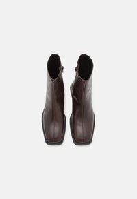 Brown leather ankle boots with a sleek design, square toe, side zippers, and textured black rubber sole. Smooth surface finish.