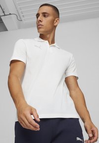 Witte polo gemaakt van gestructureerde stof, met een klassieke kraag en korte mouwen. Bevat een subtiele grijze logo op de borst.