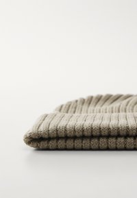 Beige gebreide beanie met ribbeltextuur, omgevouwen aan de rand. Zacht materiaal, nauwsluitend patroon en geen zichtbare logo's of versieringen.