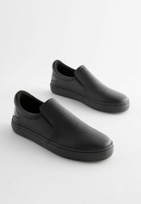 Pantofi negri slip-on din piele texturată, cu o talpă plată neagră și accente laterale; design minimalist fără șireturi.
