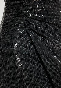 Rochie neagră cu paiete, având o textură gathered. Țesătura este împodobită cu paiete strălucitoare și reflective și are un design asimetric.