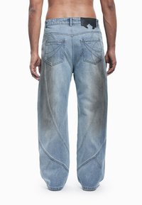 Svetlo modre jeans hlače širokega kroja z značilnimi vzorci šivov, dvema zadnjima žepoma in teksturiranim logotipom na pasu.