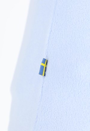 Hellblaues Fleece-Gewebe mit einem kleinen schwedischen Flaggenetikett, das in die Naht eingenäht ist und eine strukturierte Oberfläche zeigt.