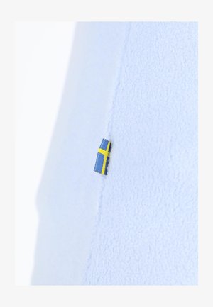 Hellblaues Fleece-Gewebe mit einem kleinen schwedischen Flaggenetikett, das in die Naht eingenäht ist und eine strukturierte Oberfläche zeigt.