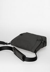 Grau Leder Umhängetasche mit verstellbarem Tragegurt, minimalistisches Design, glatte Textur und dezentes Logo-Detail.