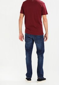 Mörkröd t-shirt i kombination med mörkblå denimjeans, med rakt ben och tre bakfickor med böjda sömmar.