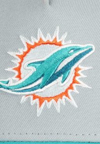 Hellgraue Stoffmütze mit einem gestickten türkisfarbenen Delfin-Logo und orangefarbenen Sonnenstrahlen-Akzenten. Strukturierte Oberfläche mit einem sportlichen Design.