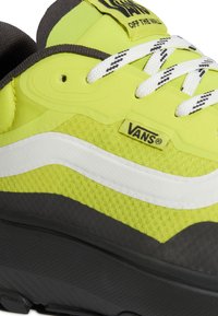 Baskets Vans jaunes et noires avec bande blanche et lacets, logo Vans visible et étiquette « Off The Wall » sur la languette.