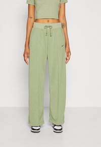 Světle zelené sportovní kalhoty s elastickým pasem, bočními kapsami a jemným logem Nike. Měkká, hladká tkanina, volný střih pro pohodlí.