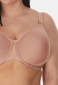 Reggiseno con ferretto di un delicato beige chiaro, dotato di coppe modellate lisce, dettagli in pizzo sulle spalline e un'apertura a chiave al centro. Caratterizzato da spalline regolabili.