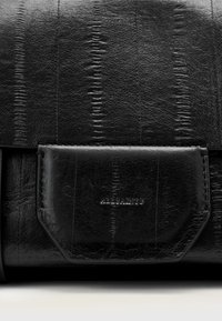 Borsa in pelle nera con motivo testurizzato, dotata di chiusura a patta e marchio in rilievo. Finitura liscia con una forma strutturata.