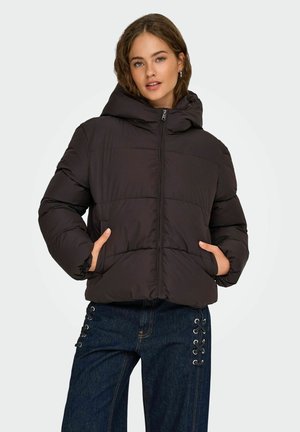 Veste matelassée noire avec une capuche, dotée d'une fermeture éclair à l'avant, de deux poches latérales et d'un design volumineux. Portée sur un jean bleu avec des détails en lacet.
