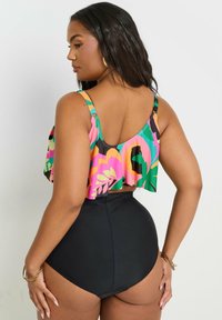 Färgglad blommig mönstrad tankini-top med volangärmar, ihop med högmidjade svarta baddräktsbyxor, slät textur och justerbara axelband.