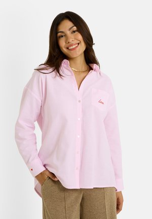 Chemise à rayures rose clair avec un design à boutons, une poche poitrine avec "Love" en rouge, et des manches retroussées avec un accent en forme de cœur.