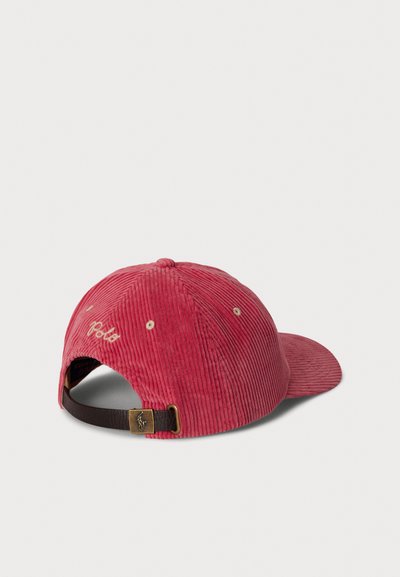 Gorra de pana roja con visera curva, tela texturizada, correa ajustable marrón contrastante y logo "Polo" bordado en la parte trasera.