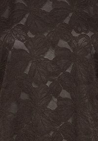 Tessuto in pizzo marrone scuro con un design floreale caratterizzato da dettagliate cuciture e una texture trasparente, che mette in evidenza forme e motivi di petali intricati.