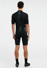 Maillot de vélo noir à manches courtes, présentant des accents en lignes verticales dans le dos. Assorti à un short noir rembourré, conçu pour le confort et le soutien.