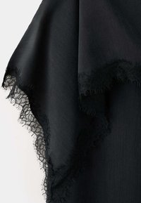 Tissu noir avec une délicate bordure en dentelle florale le long des bords, montrant la texture et des détails finement effilochés sur un fond clair.