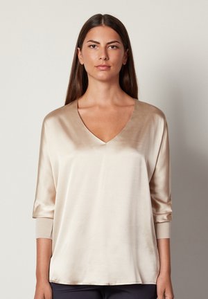 Beige Satinoberteil mit V-Ausschnitt und Dreiviertelärmeln. Weicher Stoff, lockere Passform und gerippte Ärmelabschlüsse.