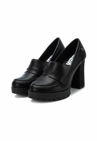 Tacones de plataforma de cuero negro con puntera redondeada, una correa decorativa y un tacón de bloque alto y grueso. Suela texturizada para agarre.
