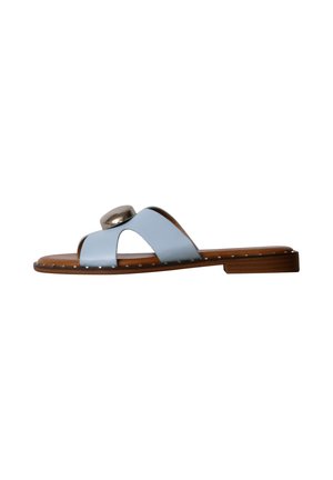 Sandale plate marron avec des brides croisées bleu clair et un gros bouton décoratif argenté sur le dessus, clous en métal le long du bord de la semelle.