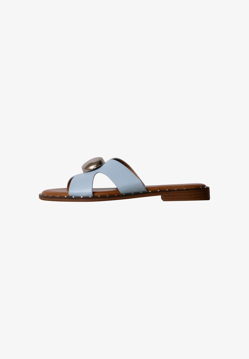 Sandale plate marron avec des brides croisées bleu clair et un gros bouton décoratif argenté sur le dessus, clous en métal le long du bord de la semelle.