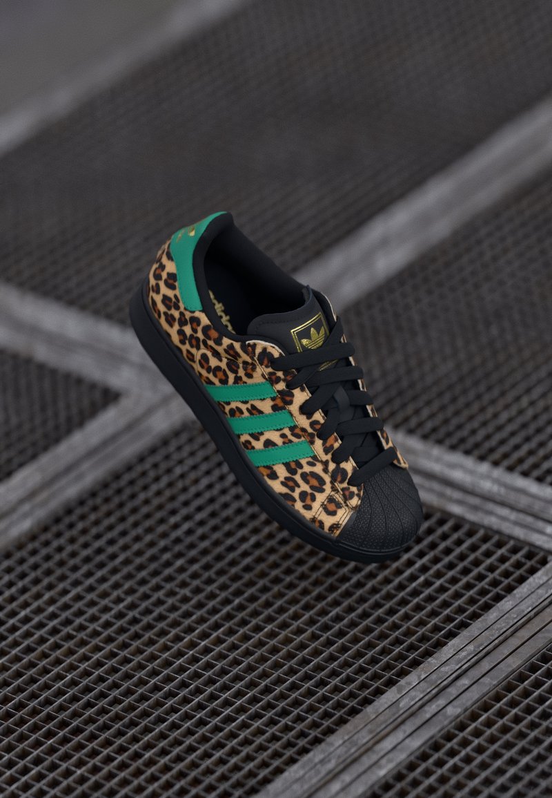 Sneaker con stampa leopardata, punta nera, accenti verdi e lacci neri. Presenta tre strisce verdi e un logo sulla linguetta.