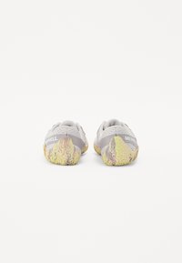 Baskets de sport grises avec une tige en mesh, une semelle en caoutchouc texturé avec des accents jaunes, et un design profil bas adapté aux activités de plein air.