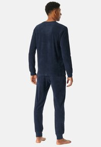 Marineblå fleece-loungewear sæt med langærmet top og taperede bukser med ribbede manchetter, blød tekstur og en afslappet pasform.