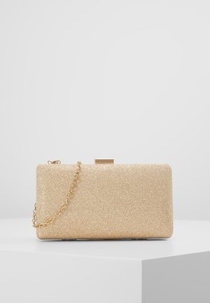 Rektangulær clutch taske med guldfarvet glimmer og en guldkæde som strop, hvilende på en hvid overflade mod en lysegrå baggrund.