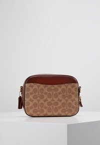 Beigen kuvioitu kangaskassi, jossa ruskeat nahkaosat, suorakaiteen muotoinen, yläreunassa vetoketjusulku, säädettävä olkahihna ja kullanväriset metalliosat.