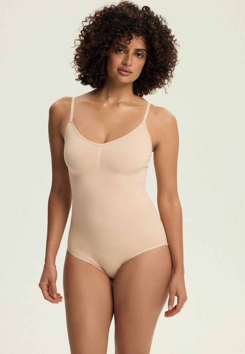 Nude bodysuit with thin adjustable straps, a smooth texture, and gathered detail at the bust, featuring a fitted silhouette.