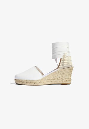 Witte espadrille sleehak met een jute zool, een gladde stoffen bovenkant en banden om de enkel. De hak heeft een textuurgeweven accent.