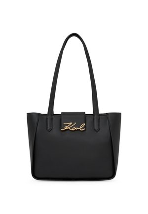 Black leather tote bag with two handles, featuring a structured shape and a gold-tone signature logo on the front. Smooth texture.