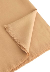 Vaaleanbeige kangas, jossa on pehmeä rakenne, esittelee hieman purkautunutta reunaa ja sileää puolta, taitettuna kolmion muotoon.