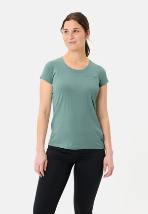 Hellgrünes, kurzärmliges T-Shirt aus weichem Stoff, mit rundem Halsausschnitt und kleinem Logodetail auf der Brust. Kombiniert mit schwarzen Leggings.
