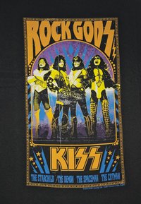 Černé tričko s barevným grafikou a textem "ROCK GODS" a čtyřmi stylizovanými postavami, z nichž každá je oblečena v odlišném rockovém kostýmu.