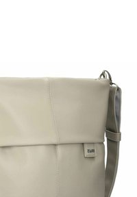 Borsa in pelle beige con una superficie liscia, forma rettangolare, pattina pieghevole e dettagli in metallo argentato, con un'etichetta del logo del marchio visibile.
