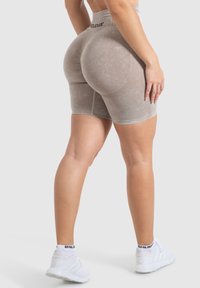 Shorts atletici beige a vita alta realizzati in un tessuto texturizzato, caratterizzati da un design aderente con accenti a coste e dettagli di cuciture piatte.