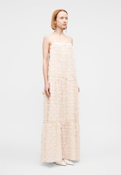 Robe longue en tissu pêche clair avec appliqués floraux, bretelles spaghetti, design en couches et silhouette fluide. Chaussures à bout pointu mate.