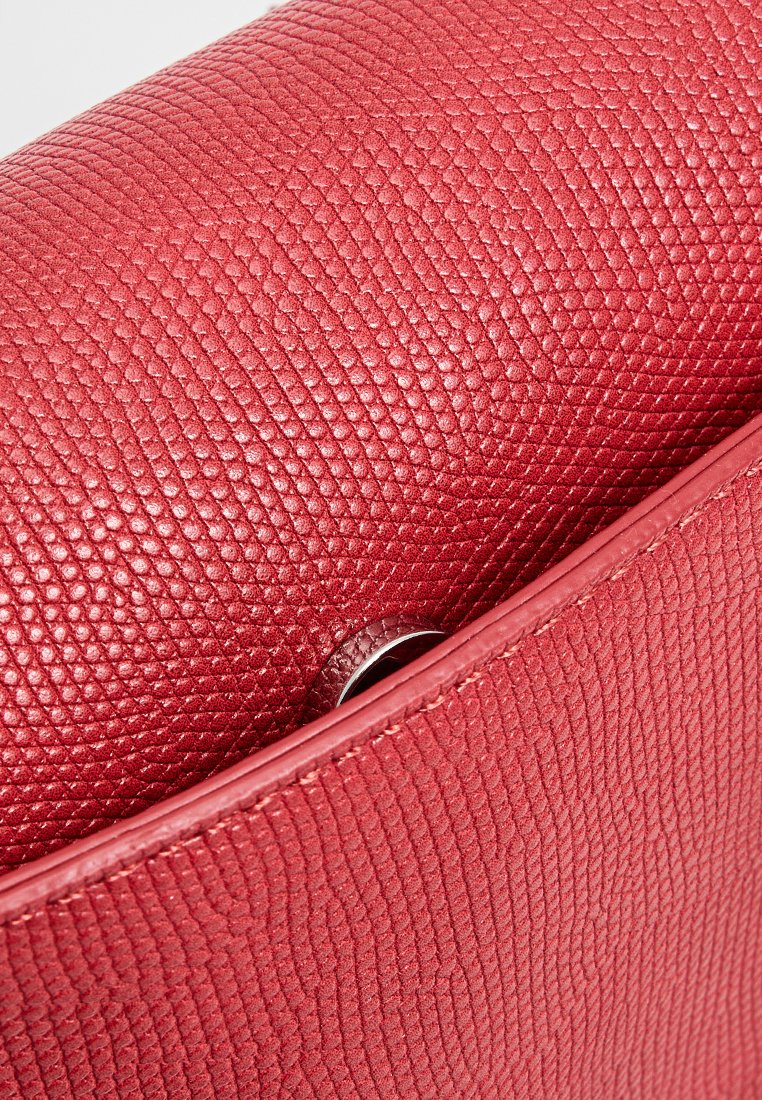 Czerwona torebka teksturowana z wykończeniem z pebble leather, z detalem z srebrnego metalu przy zapięciu i gładkimi brzegami.