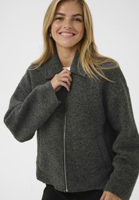 Grau-wollene Jacke aus einer Wollmischung mit Reißverschluss, weitem Kragen und übergroßen Ärmeln. Verfügt über seitliche Taschen und eine strukturierte Oberfläche.