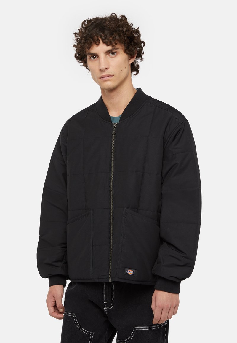 Doudoune noire avec fermeture éclair à l'avant, motif matelassé, poignets côtelés et deux poches avant. Matière douce avec une coupe décontractée.