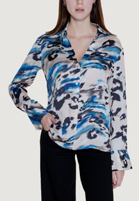 Hemdbluse aus leichtem, seidig-weichem Stoff mit cremefarbener Basis, blauen und schwarzen abstrakten Mustern sowie langen Ärmeln mit ausgestellten Manschetten.