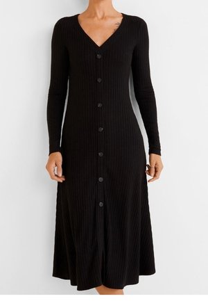 Robe midi noire côtelée à manches longues avec col en V et boutons sur le devant, portée par une personne debout sur fond blanc.