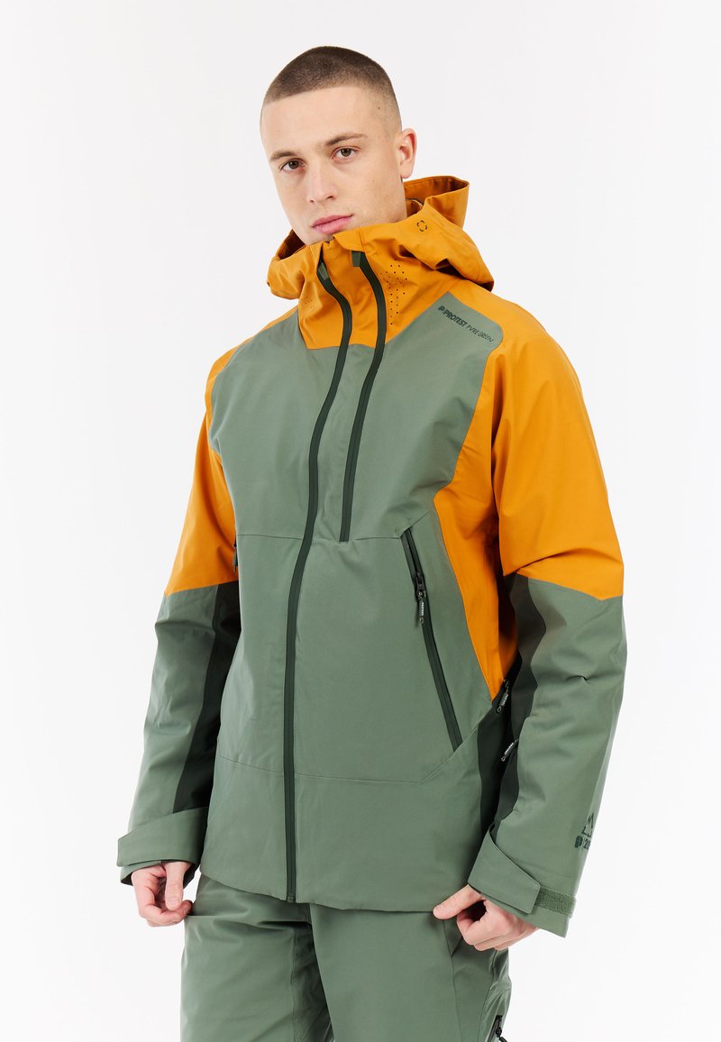 Waterdichte jas in groene en oranje kleurvlakken. Beschikt over een hoge kraag, ritszakken en een verstelbare capuchon voor extra functionaliteit.