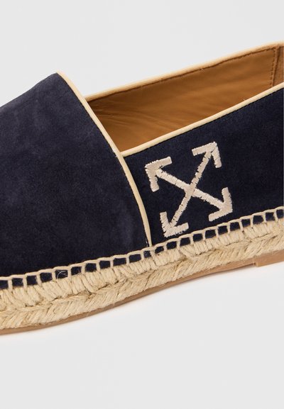 Námořnické modré semišové espadrilky s béžovým prošíváním, přírodní jutovou podrážkou a vyšitým bílým logem šípů na boku.