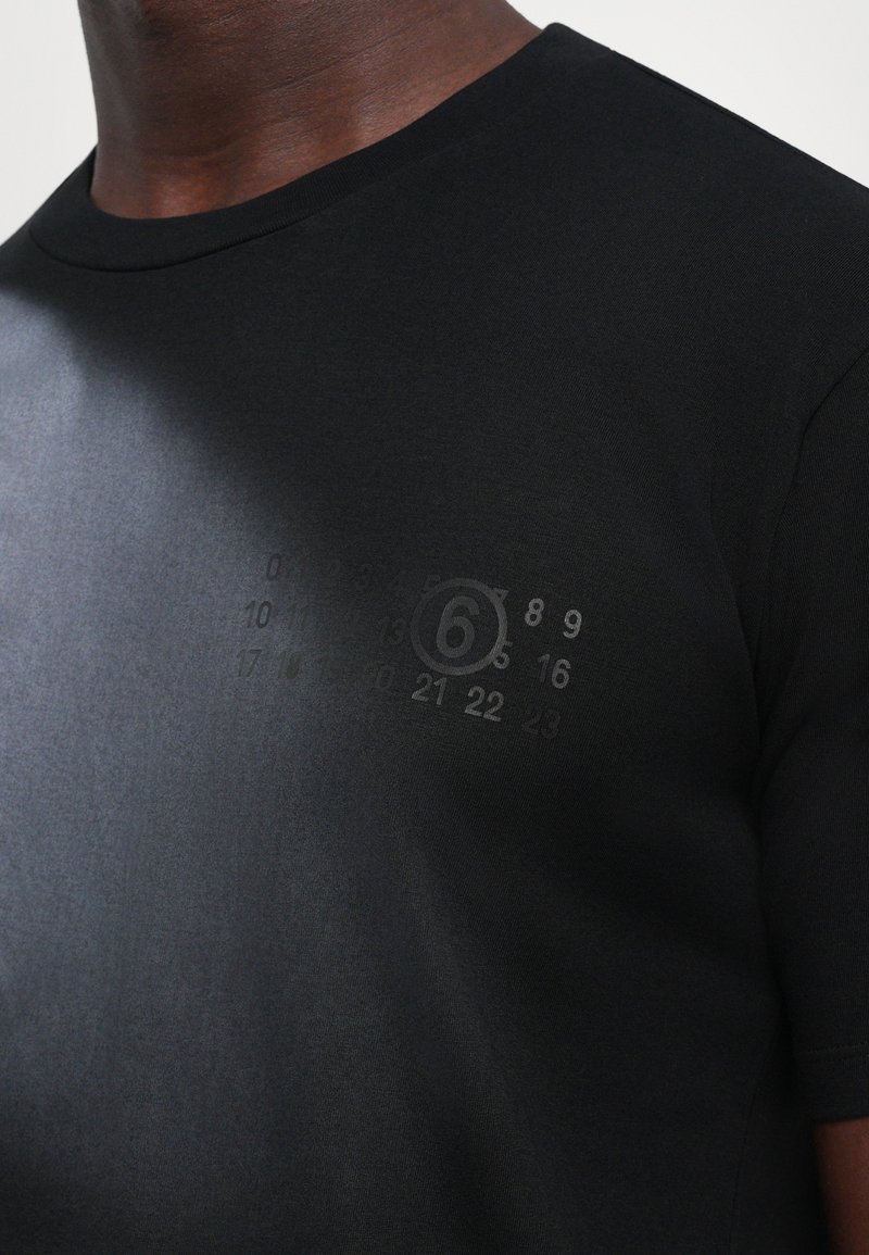 Sort bomulds t-shirt med rund halsudskæring, korte ærmer og et subtilt print med tal og tallet "6" på brystet.